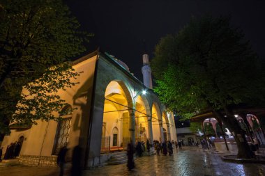 SARAYBOSNIA HERZEGOVINA - 15 Nisan 2017: Saraybosna 'daki Gazi Husrev Begova camii önünde namaz kılan insanlar. Cami, başkent Bosna 'nın sehpanın başlıca simgesi.
