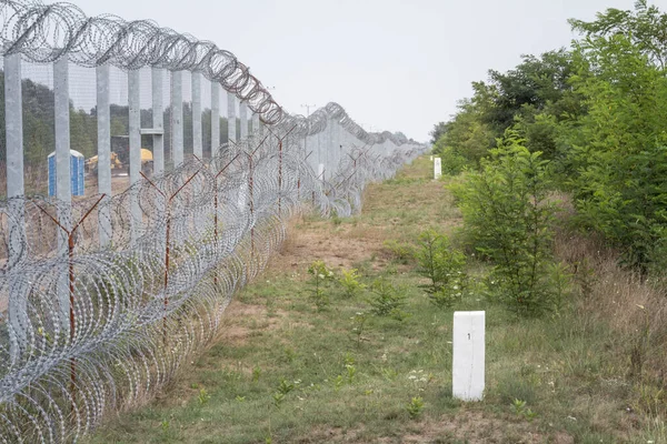 Border fence between Subotica (Serbia) & Kelebia (Hungary) with boundary marker. This border wall was built to stop the incoming refugees & migrants during the refugees crisis, on Balkans Route