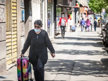BELGRAD, SERBIA - 27 Nisan 2020: Coronavirus covid 19 sağlık krizi sırasında Belgrad caddesinde yürüyen, solunum maskesi takan yaşlı kadın
