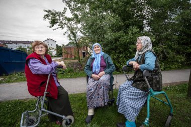 BRCKO, BOSNIA, 6 Mayıs 2017: Geleneksel Müslüman atkısını takan kıdemli Boşnak Kadınlar, Bosna 'nın Brcko kentinin sokaklarında oturan ve dostlar arasında tartışıyor