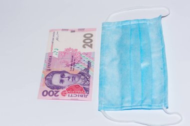 Koruyucu tıbbi maske ve beyaz arka planda Ukrayna Hrivnia 'sı. Pahalı tıp konsepti.
