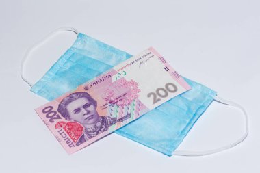 Koruyucu tıbbi maske ve beyaz arka planda Ukrayna Hrivnia 'sı. Pahalı tıp konsepti.