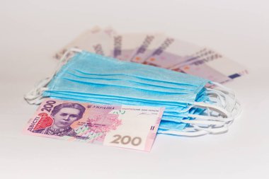 Koruyucu tıbbi maske ve beyaz arka planda Ukrayna Hrivnia 'sı. Pahalı tıp konsepti.
