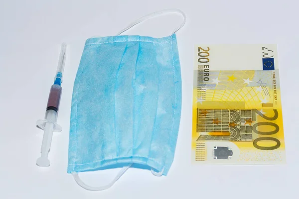 Koruyucu tıbbi maske, şırınga aşısı ve euro faturaları. Pahalı tıp konsepti.