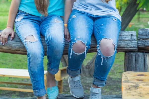 Yırtık kotlu kadın bacakları ve dizleri. Kızlar için şık kotlar. Delikli pantolonlar, hipster, sokak modası. Yaz için giysiler. Mevsim bahar-yaz.