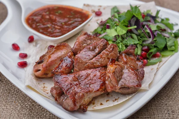 Beyaz bir plaka üzerinde domuz eti şiş kebap