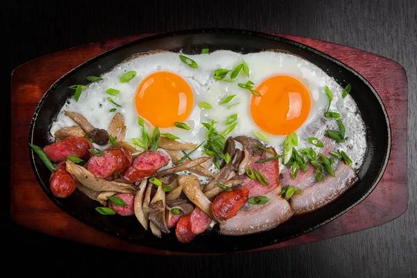 Жареные яйца с беконом, колбасой и зеленью — стоковое фото