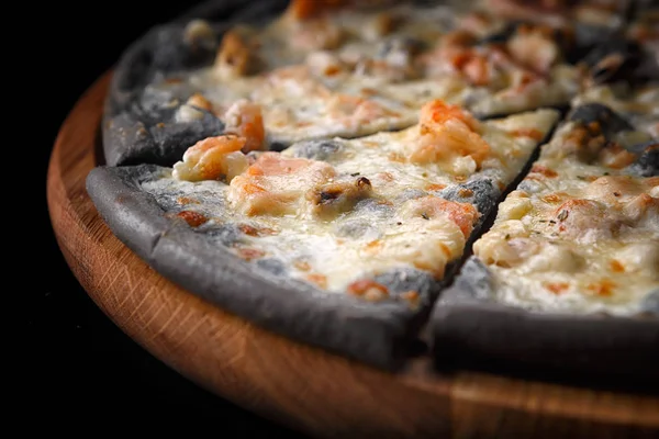 Black pizza on a wooden board