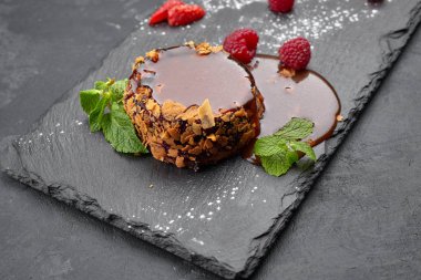 Koyu arkaplanda karamel olan yuvarlak peynirli kek.