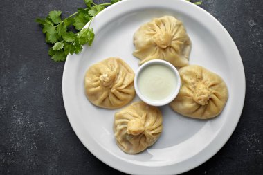 Khinkali soslu ve otlu, koyu bir arka planda kaynatılmış.