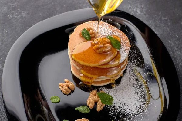 Buñuelos con miel y nueces en un plato negro —  Fotos de Stock