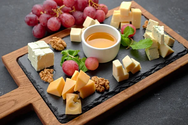 Assorted cheese (cheese board) on a black background