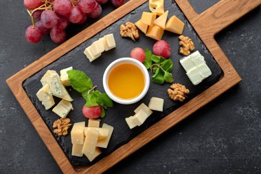 Siyah arkaplanda çeşitli peynirler (peynir tahtası)