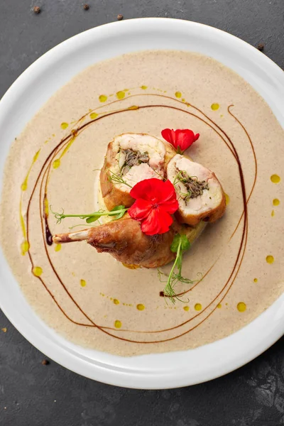 Gamba d'anatra ripiena con salsa, su un piatto bianco, su uno sfondo scuro — Foto Stock