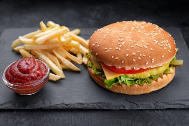 Et, patates ve soslu çizburger, siyah arka planda.