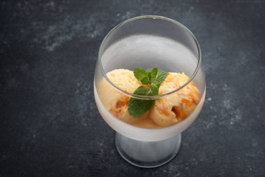 Cam bir kadehte balkabağı dondurması, siyah bir arka planda, tahta bir tahtayla.