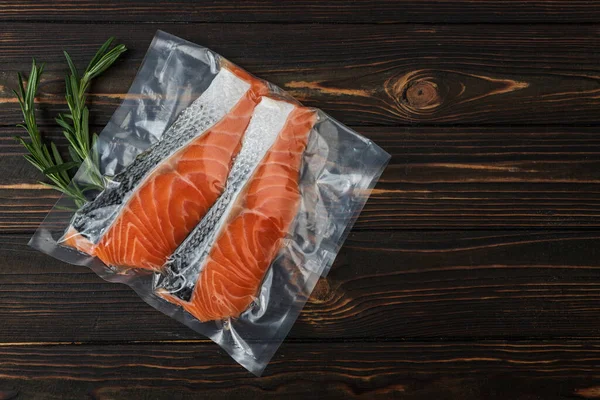 Vacuum-packed fish, trout, salmon on a wooden board. Top view.