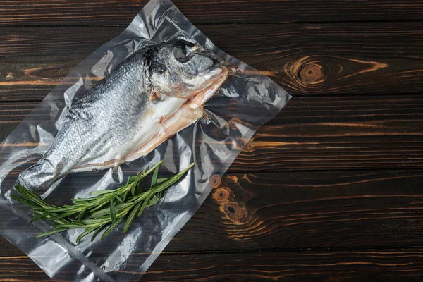 Vacuum-packed fish, dorado on a wooden board. Top view.