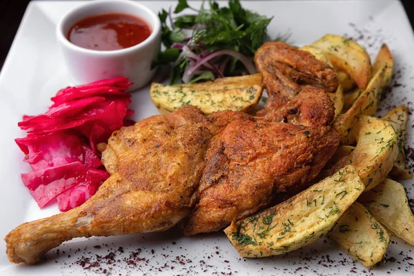 Yarım tütün tavuğu, beyaz tabakta patates ve sos.