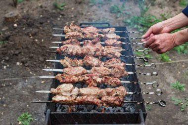 Adam takla atıyor, ızgarada barbekü pişiriyor, açık havada.