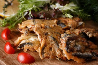 Tahta bir tahtanın üzerinde hamurda kızartılmış spagetti kekleri, otlar, domates ve limonla birlikte.