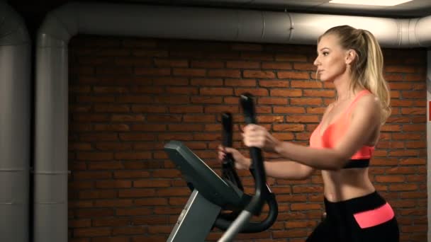 Vacker kvinna stående på gymmet cykling — Stockvideo