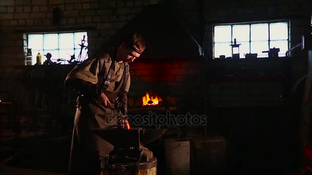 Ferreiro traz gotejamento de metal quente do forno e cria uma chuva de faíscas como ele bate um pedaço de metal quente branco com um martelo em uma bigorna . — Vídeo de Stock