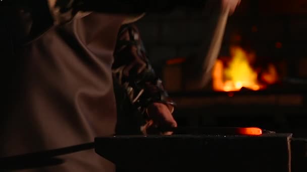 Ferreiro traz pingando metal quente do forno e cria uma chuva de faíscas como ele bate um pedaço de metal quente branco com um martelo em uma bigorna. Fechar gravado . — Vídeo de Stock
