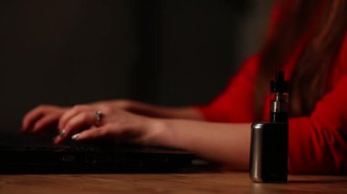 Yakın çekim esmer kırmızı ceketli diz üstü ile çalışır ve kamuya açık bir yerde elektronik sigara içiyor