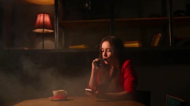 Kırmızı ceketli elektronik sigara ve cep telefonuyla konuşurken kız.