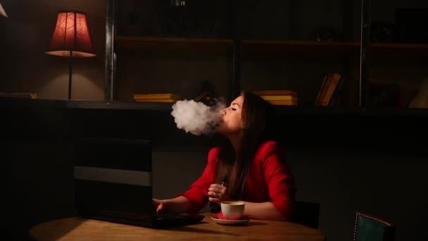 Chica trabajando con portátil bebiendo café Fumar un cigarrillo electrónico. Trabajando remotamente en un café . — Vídeos de Stock