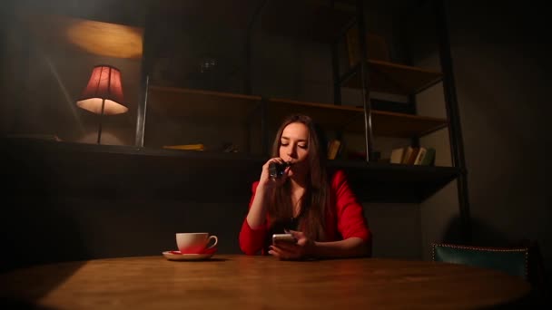 Kırmızı ceketli elektronik sigara ve cep telefonuyla konuşurken kız. — Stok video