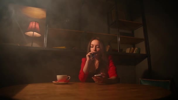 The girl in the red jacket Smoking the electronic cigarette and talking on a cell phone. — Stock Video