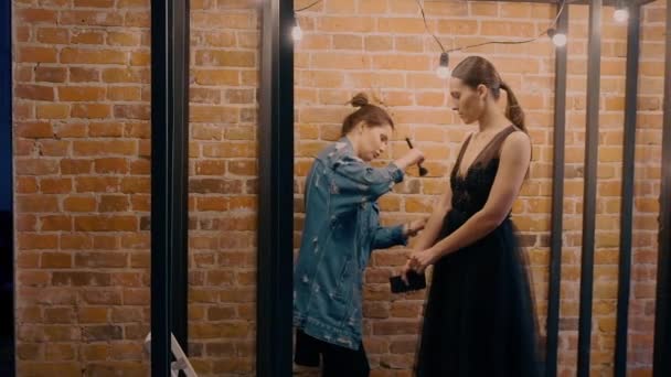 Profesionální vizážistka dělá make-up model v černé svatební šaty. Na pozadí z červených cihel a žárovky. — Stock video