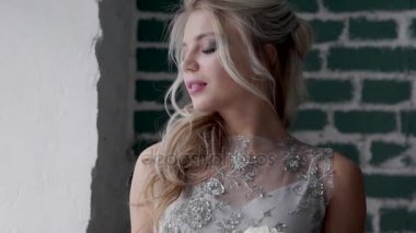 Bir gelinlik giyen, poz ve pencereden dışarı bakıp güzel sarışın model.