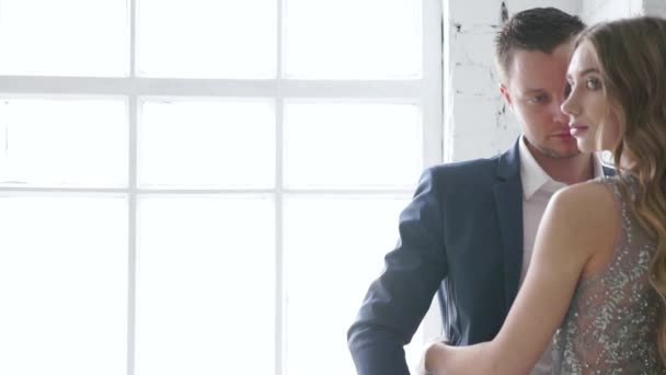 Un hombre y una niña están mirando a un amigo contra una ventana, posando para un fotógrafo, sonriendo. La pareja vulnerable. Las modelos están posando . — Vídeo de stock