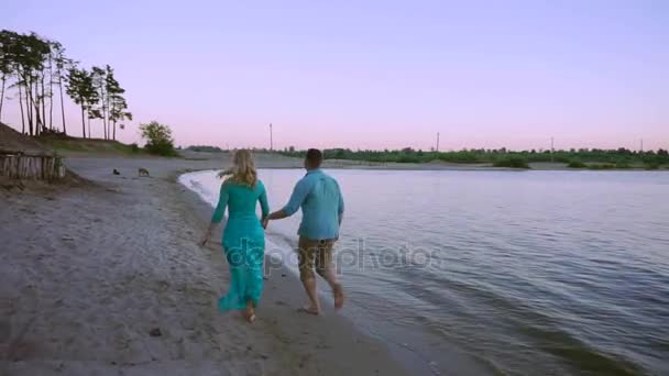 Pareja romántica caminando por una playa al atardecer — Vídeo de stock