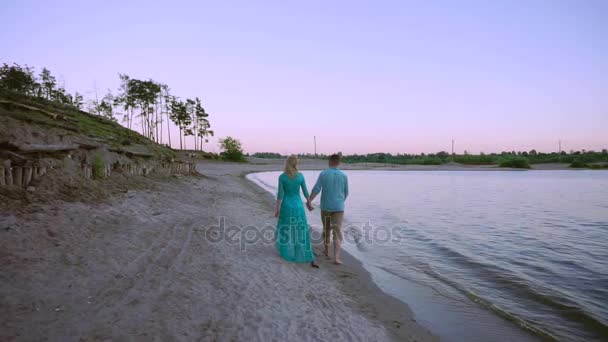 Pareja cogida de la mano en la playa puesta de sol en viaje de vacaciones de luna de miel. Feliz romántico jóvenes amantes, hombre y mujer caminando en la hermosa playa — Vídeos de Stock