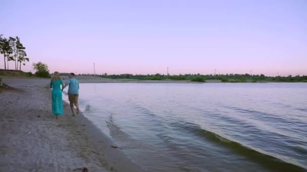 Pareja romántica caminando por una playa al atardecer — Vídeo de stock