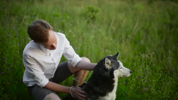 Mann und Hund sibirische Huskies Konzept. Junger Mann mit Hund auf Wiese. — Stockvideo