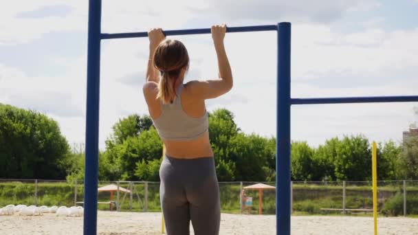 Young athletic fitness woman working out at outdoor gym doing pull ups at sunrise — Stock Video