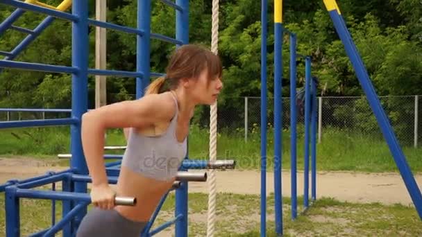 Красивая спортсменка тренируется на параллельных брусьях, делает отжимания — стоковое видео