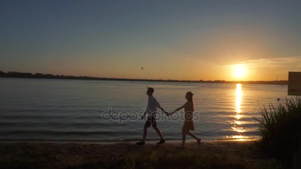 Silueta de una pareja enamorada sobre un fondo tropical al atardecer . — Vídeos de Stock