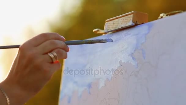 Umělec s kartáčem, namalovat obrázek na stojanu ve venkovním prostoru — Stock video