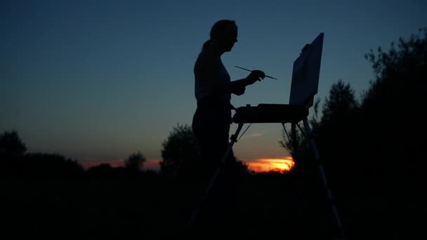 Silhouet van een meisje. Het blonde meisje schildert een schilderij op het canvas met de hulp van verven — Stockvideo