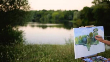 Coşku kızla boyalar bir kağıda bir manzara çizer.