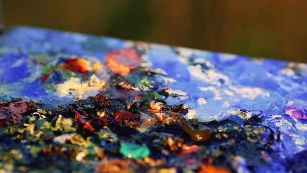Кисть художника смешать цвет живописи маслом на палитре держит в руках крупным планом — стоковое видео