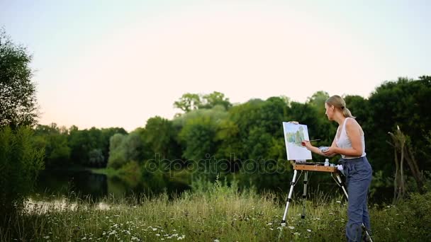 A menina com o entusiasmo desenha pinturas em um papel uma paisagem — Vídeo de Stock