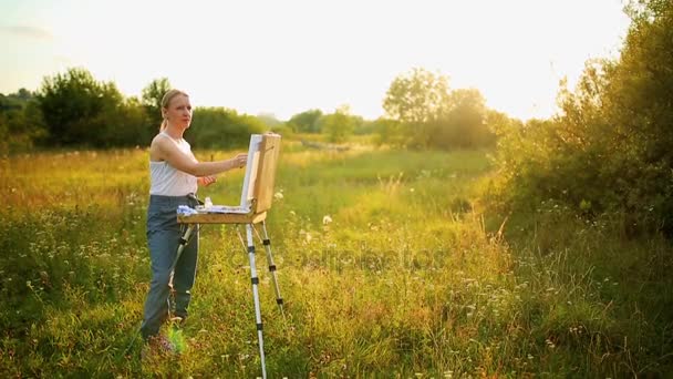 Jonge kunstenaar schilderend een herfst landschap — Stockvideo