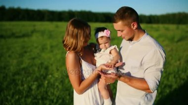 Mutlu bir aile. Baba Anne ve küçük bir kız, bir alanda yürüyüş batan güneşin ışınları altında beyaz giyinmiş